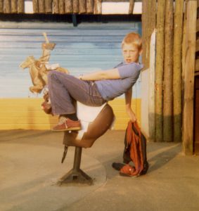 Ed posing on rocking rider in playground at Butlins, Clacton, UK, 1980s.