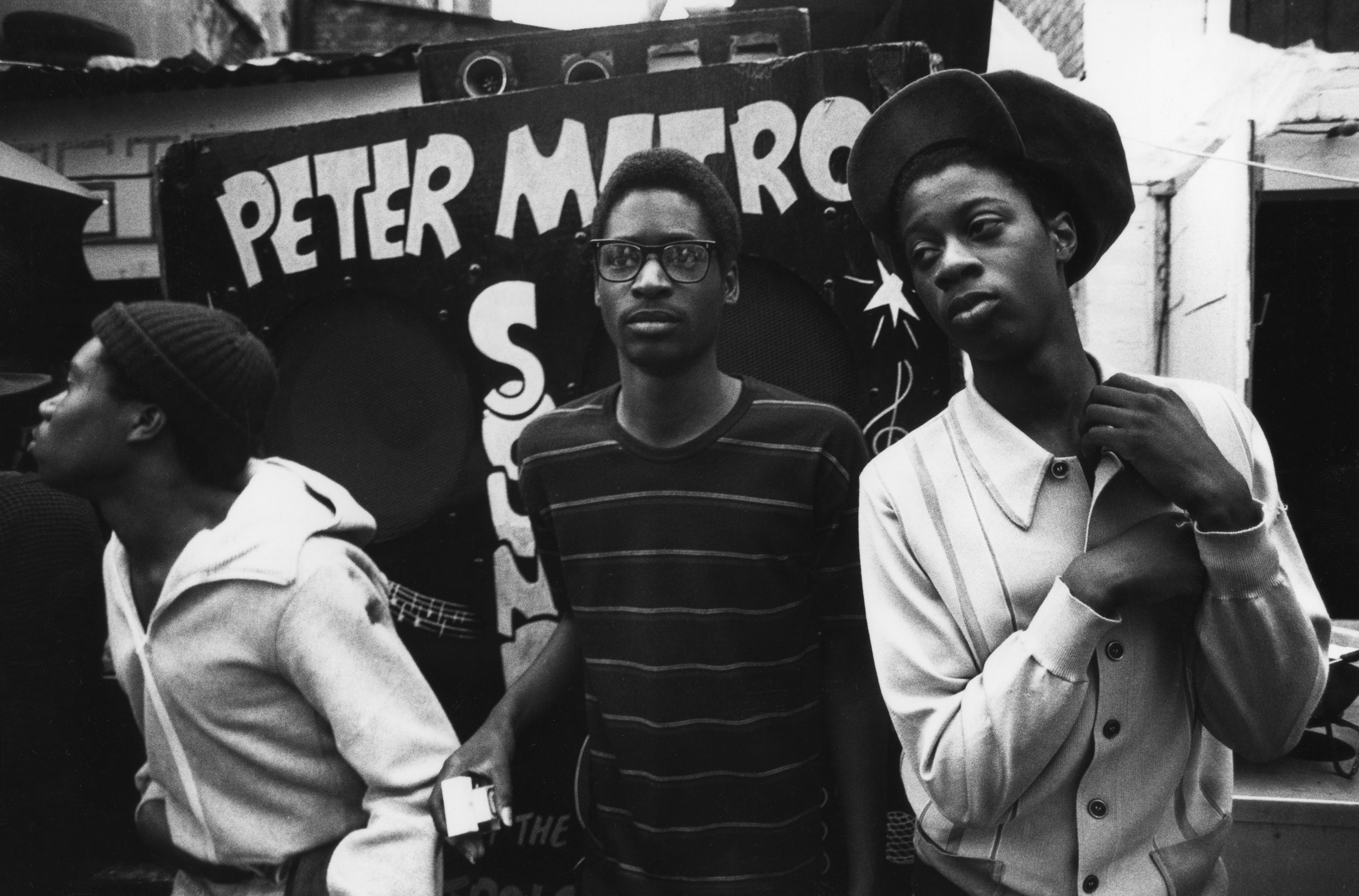 A group of men stood in front of a sound system, Notting Hill Carnival, London, A group of men stood in front of the reggae deejay 'Peter Metro' soundsystem at the Notting Hill Carnival, London, UK, August, 1983.